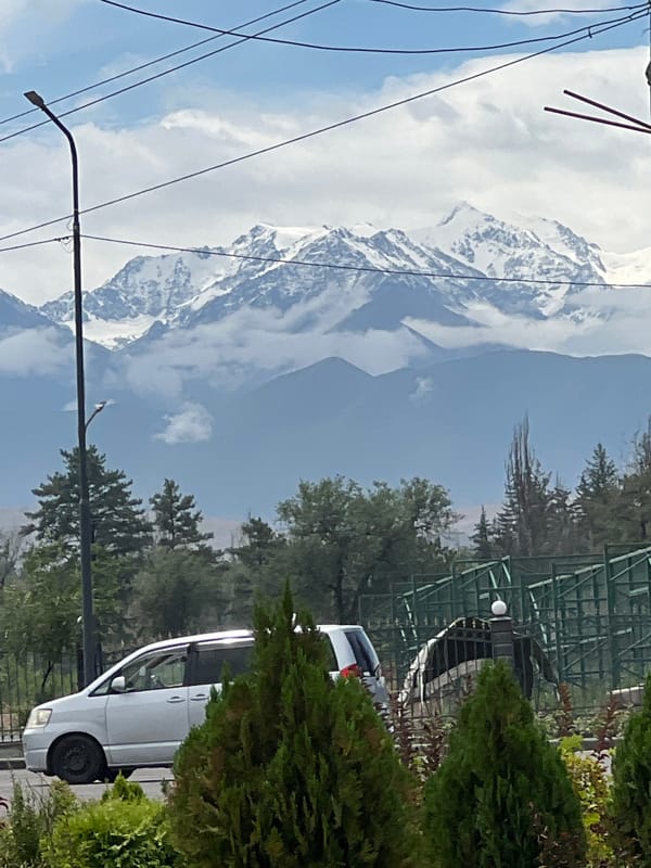 Snow-capped Tian Shan peaks loom over Bishkek on a cloudy morning