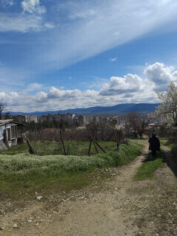 Person walks dirt path toward Kazanlak cityscape, Bulgaria