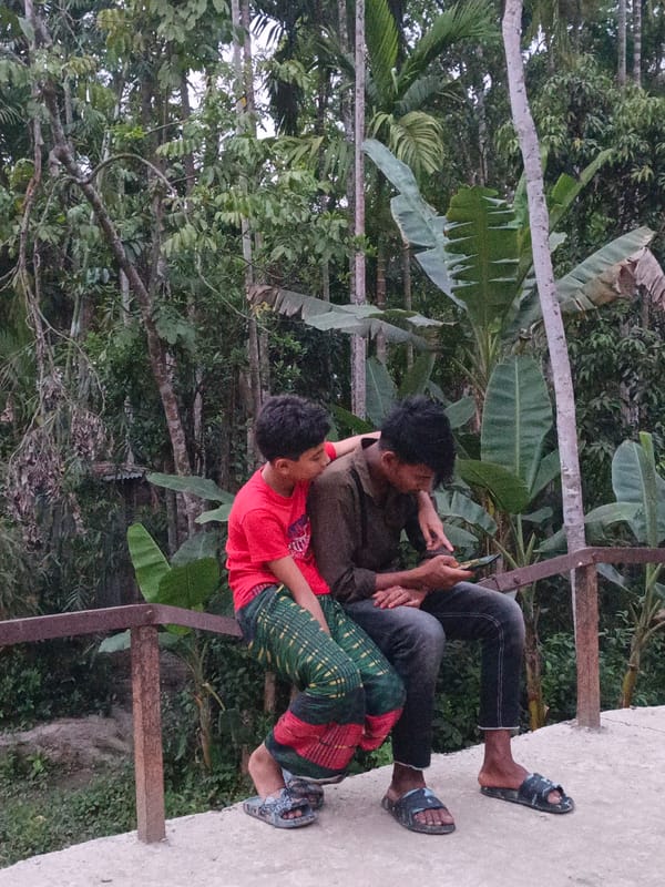 Two people rest by verdant waterside landscape in Bangladesh