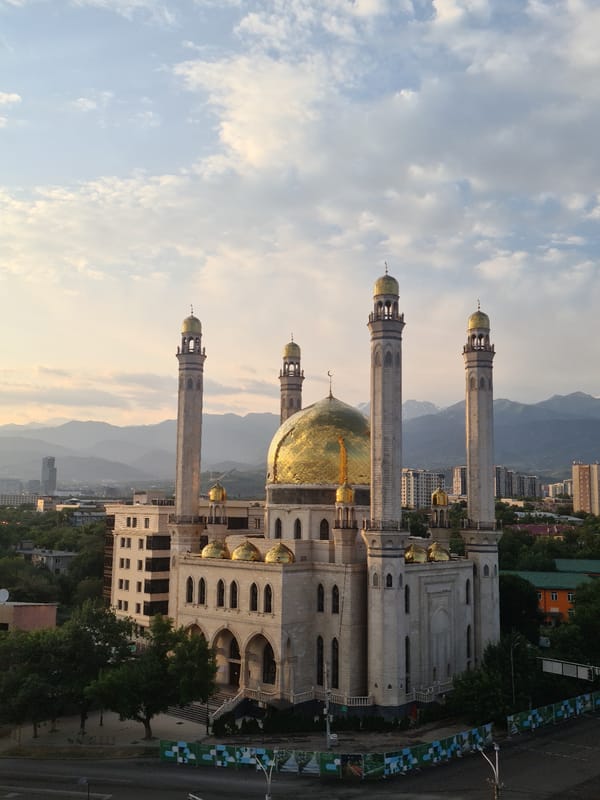 Almaty at sunset: mosque and skyline under golden skies