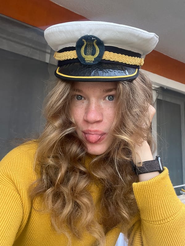 Woman applies lipstick, poses playfully in yellow sweater