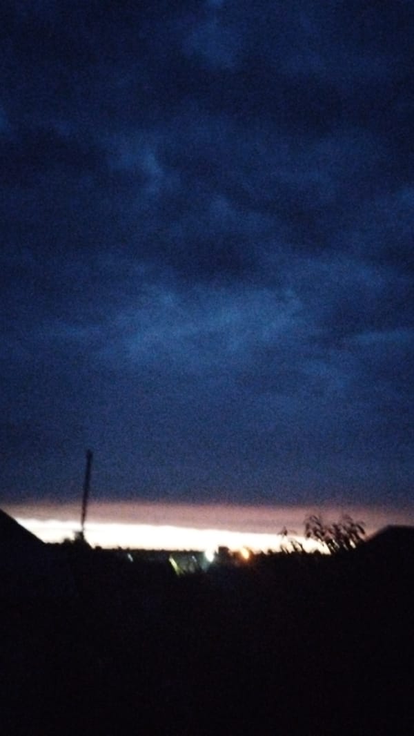 Dusk closes in across a silhouetted landscape and rooftops