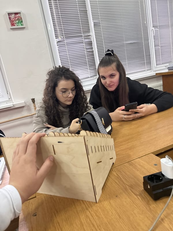 Two women examine wooden box at desk in Bulgaria