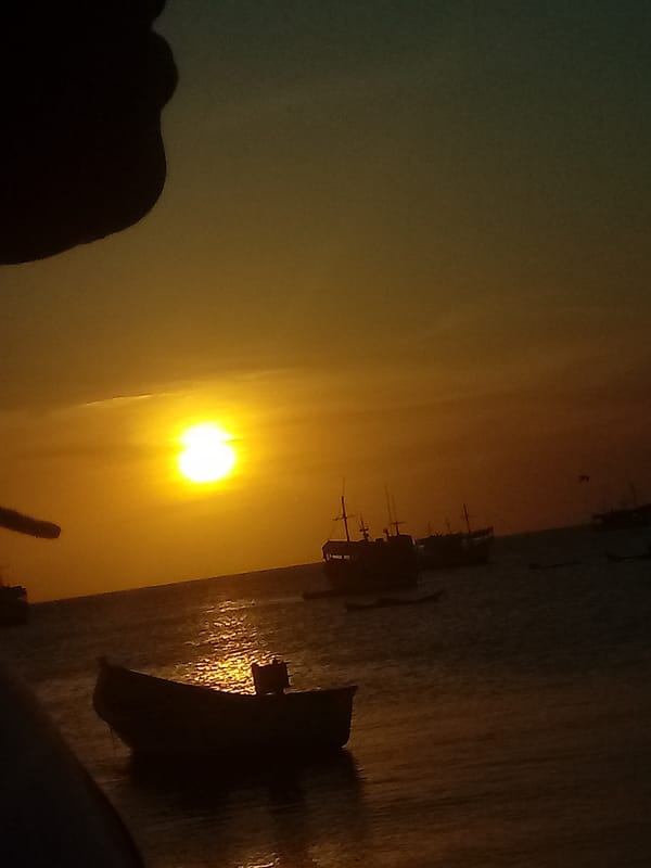 Sunset documented over Juan Griego coast with boats and street scenes