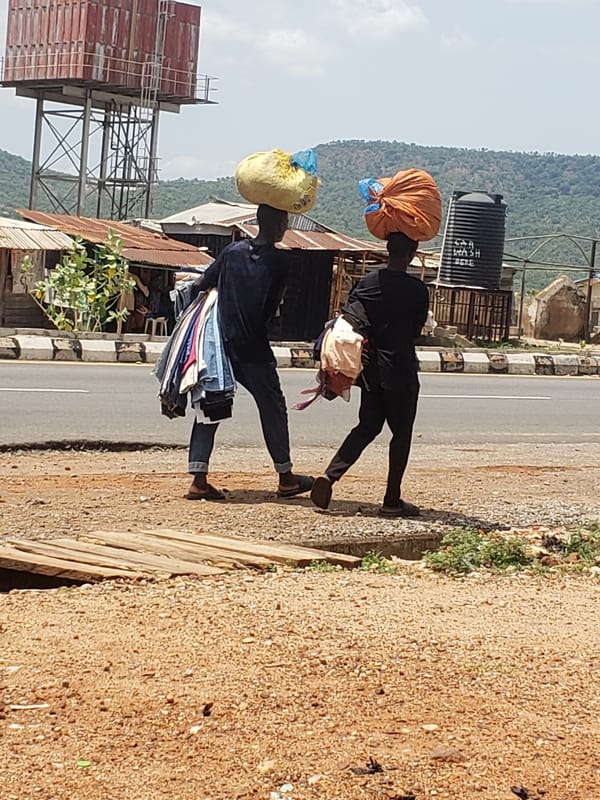 Two people carry items on heads along Adankolo road