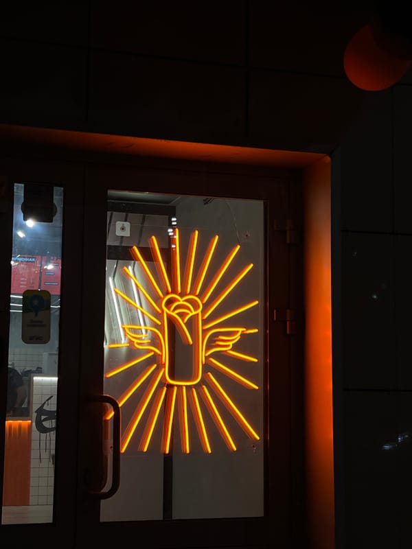 Orange neon fig sign gesture displayed in Kazan window