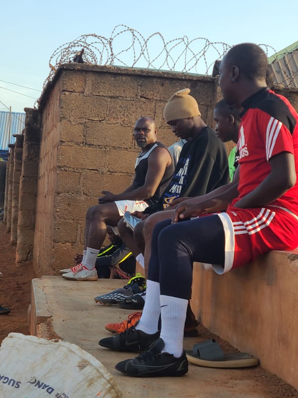 Men gather for informal soccer game on dirt field