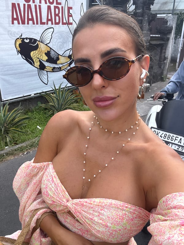 Woman in floral dress photographs herself, rides moped in Kuta
