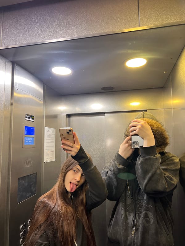 Two people take playful selfie in elevator