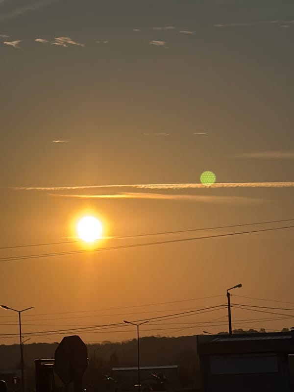 Urban sunrise captured with vapor trails and power lines