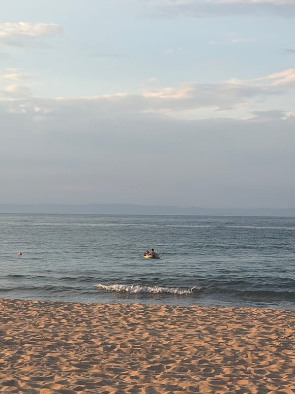 Quiet beach afternoon: wooden deck, calm water, inflatable boat.