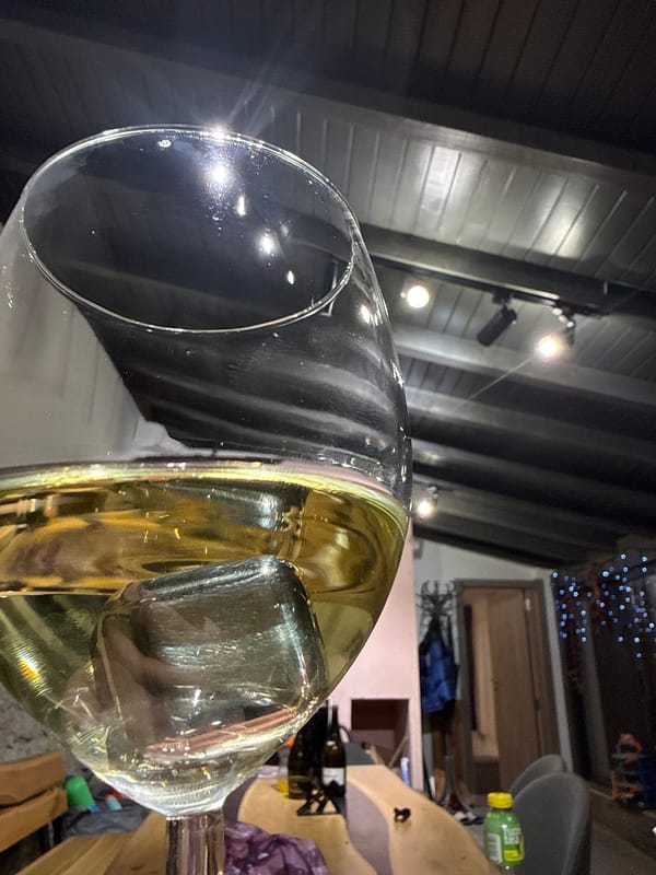 Woman enjoys wine, makes peace sign in rustic interior