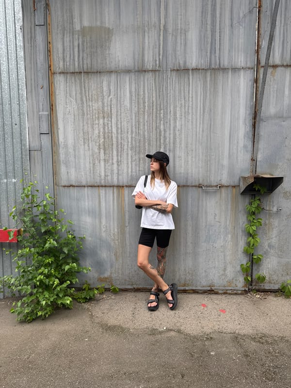 Tattooed figure poses against corrugated metal wall in Moscow