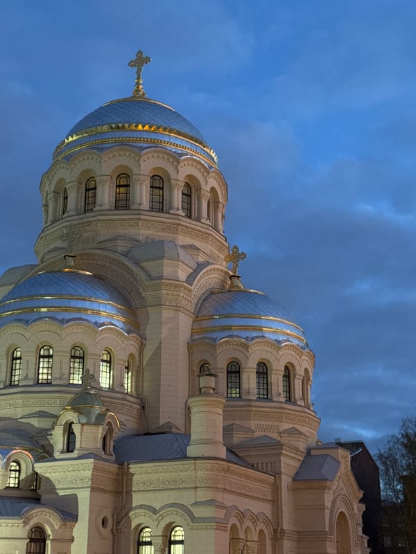Woman photographs illuminated Orthodox cathedral in Saint Petersburg evening