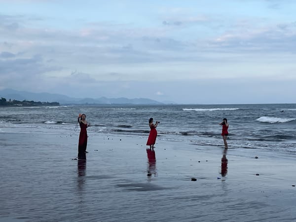 Dark sand beach and temple on a cloudy Bali morning