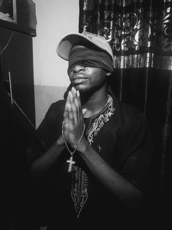 Blindfolded man in embroidered shirt documented in Lokoja, Nigeria
