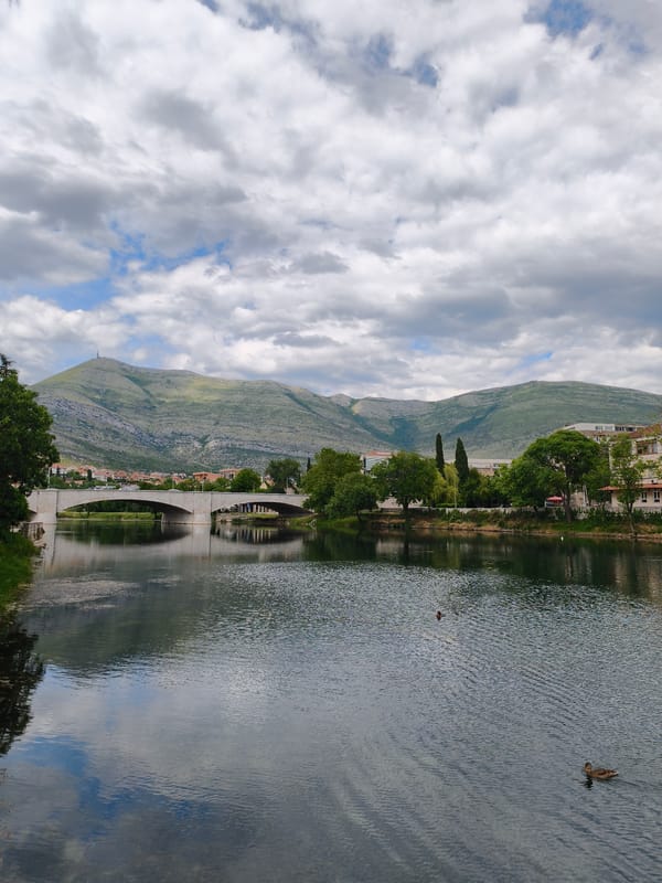 Boy feeds ducks at historic bridge in Trebinje
