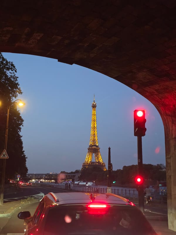 Eiffel Tower glowing at dusk, framed through a stone archway