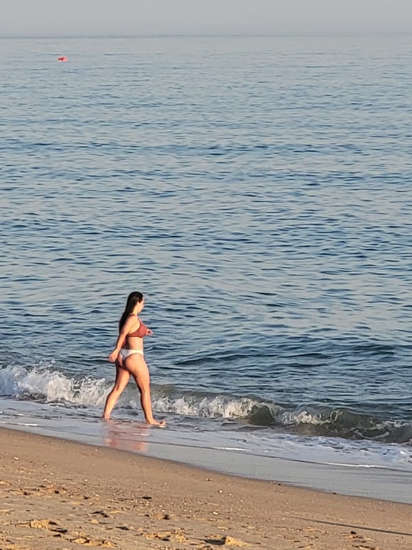 Quarteira beach at sunset, with a yacht offshore