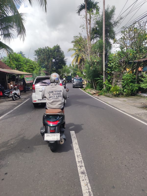 Motorcyclist in motivational sweatshirt rides through Ubud, Indonesia