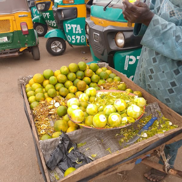 Street vendor sells oranges from wooden cart in city