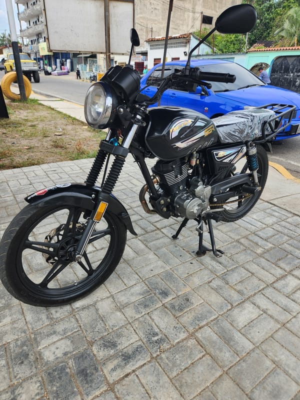 Black motorcycle parked on sidewalk in Tinaquillo, Venezuela