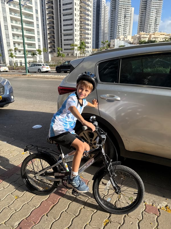 Boy on bicycle sits beside parked SUV in Netanya