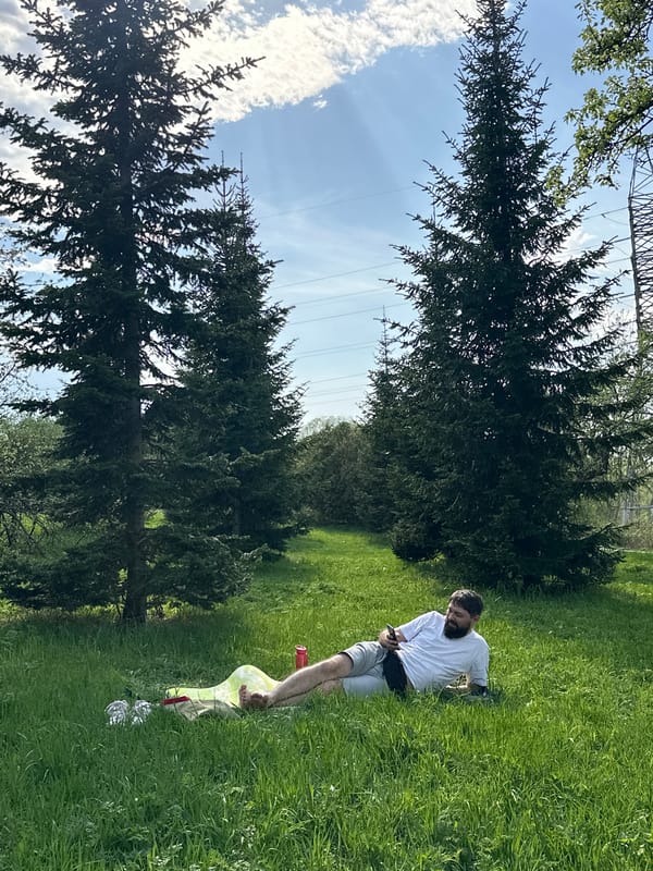 Man relaxes with phone in Moscow field after wine