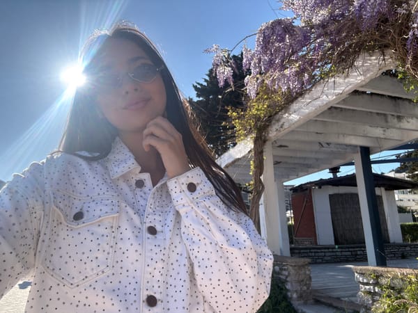 Woman takes coastal selfies near terraced buildings, mountain cityscape