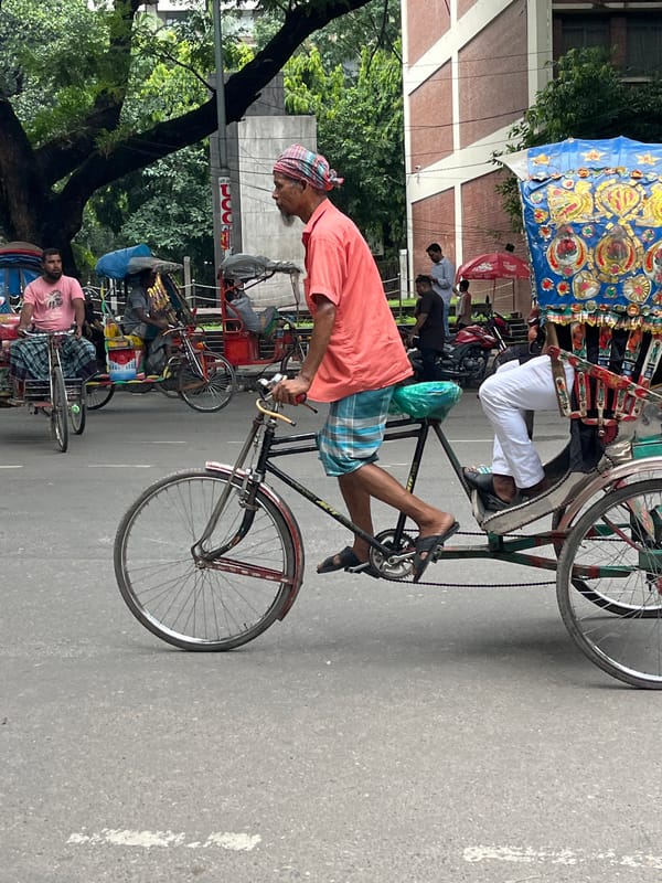 Colorful cycle rickshaws moving through a Dhaka street