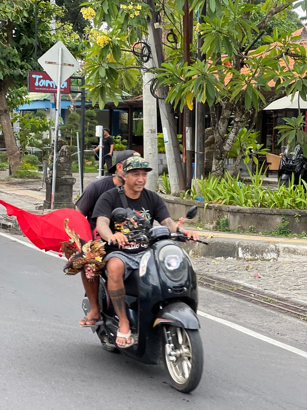 Morning street life in Denpasar — scooters, cyclists, and a garbage run