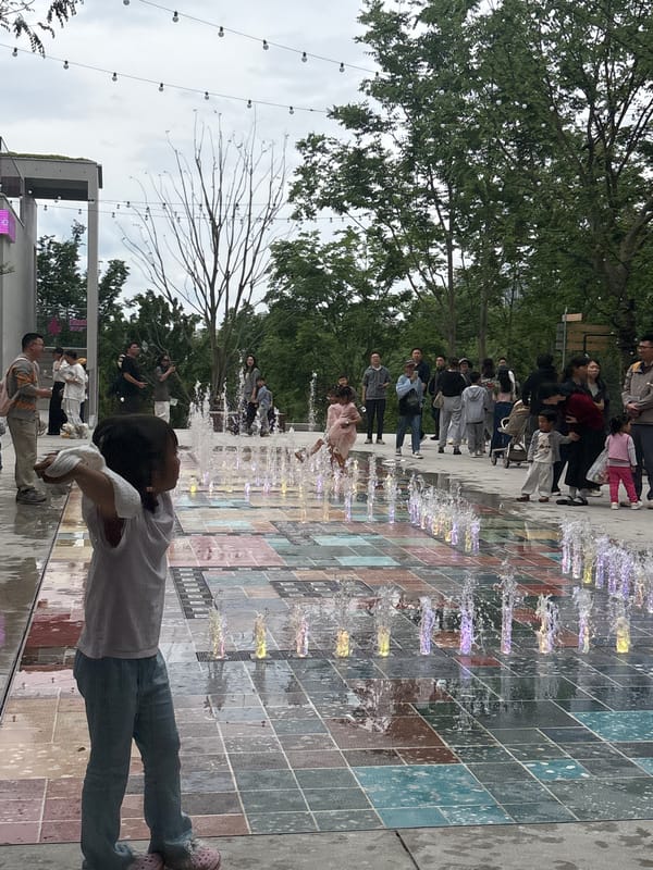 Child stands by fountain in Liangjiang street scene