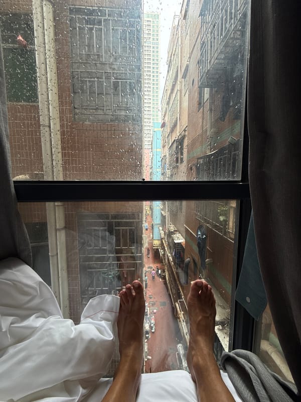 Person rests by rainy window in Futian high-rise