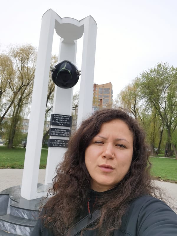 Visitors photograph monument with black sphere in Perm