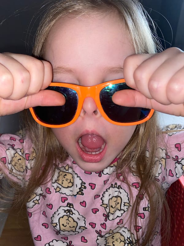 Child plays with orange sunglasses during sunset in Votkinsk