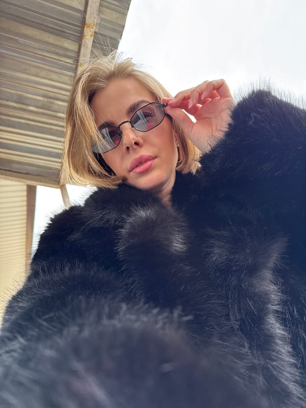 Woman in fur coat poses with sunglasses in Chaikovsky