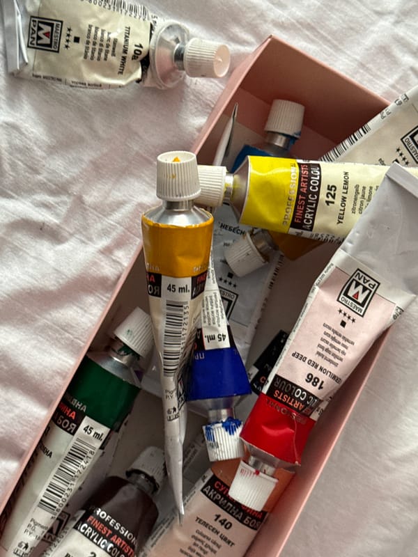 Artist's workspace captured with paints, brushes, and nude paintings