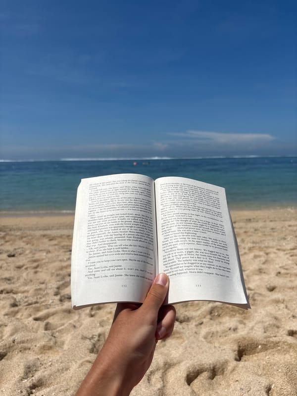 Beachgoer reads Handmaid's Tale at Kuta Selatan Indonesia beach