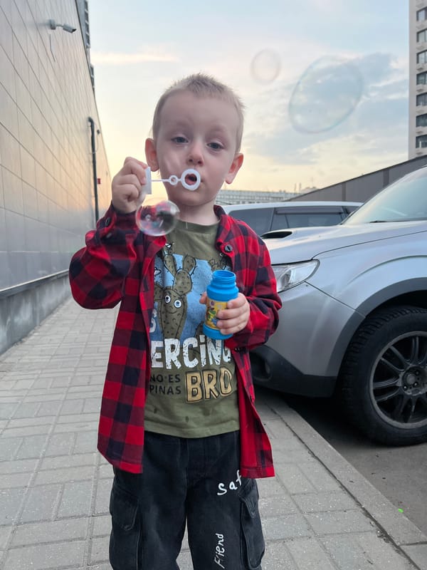 Boy plays with bubbles near motorcycle in Mytishchi evening scene
