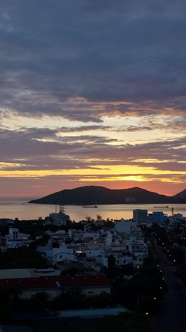 Coastal city sunset, sky shifting from blue to orange