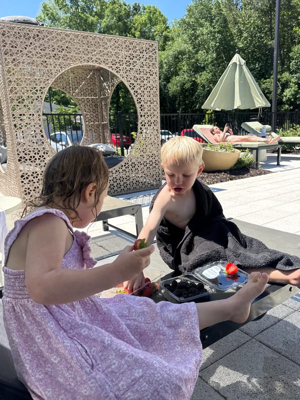 Family enjoys poolside afternoon with children sharing strawberries
