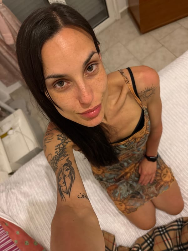 Woman with tattoos rests on sofa in Chania