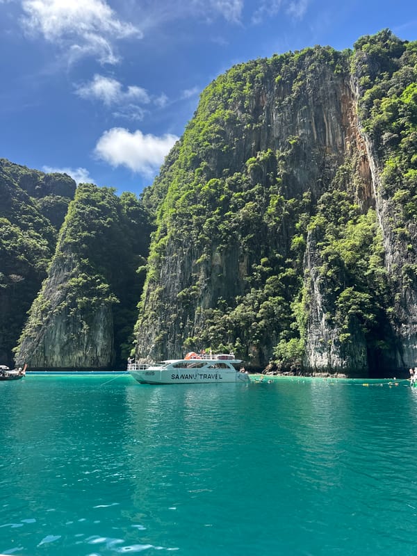 Boats navigate turquoise waters below Phi Phi Islands' limestone cliffs