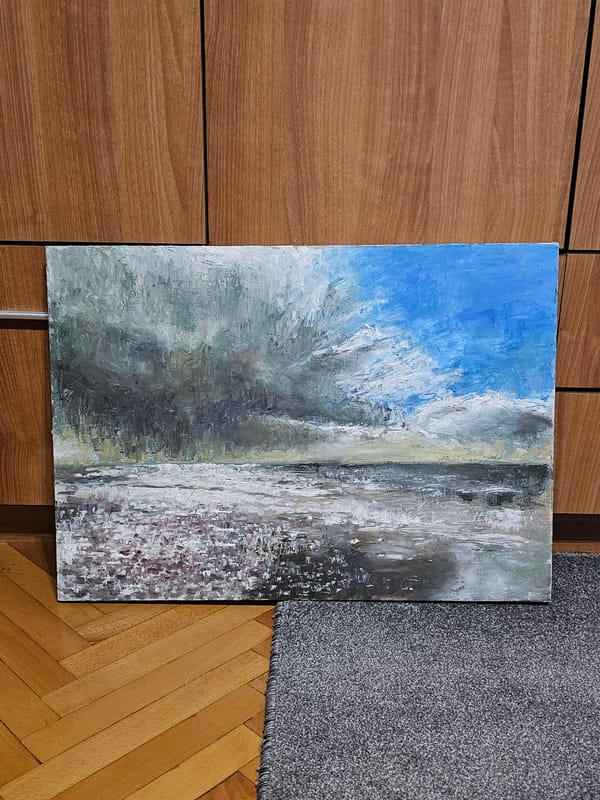 Oil painting with sky and landscape observed against wooden wall