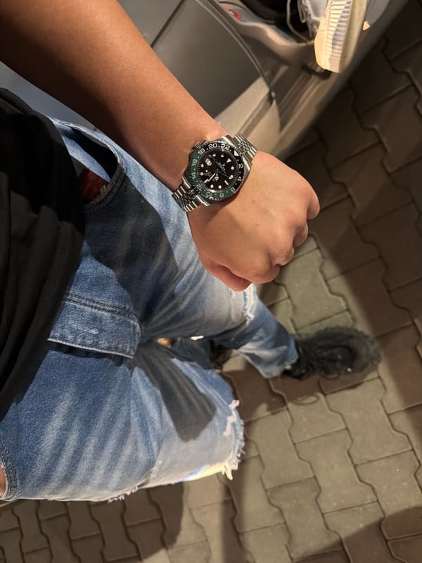 Young men with luxury watches gather around car at night
