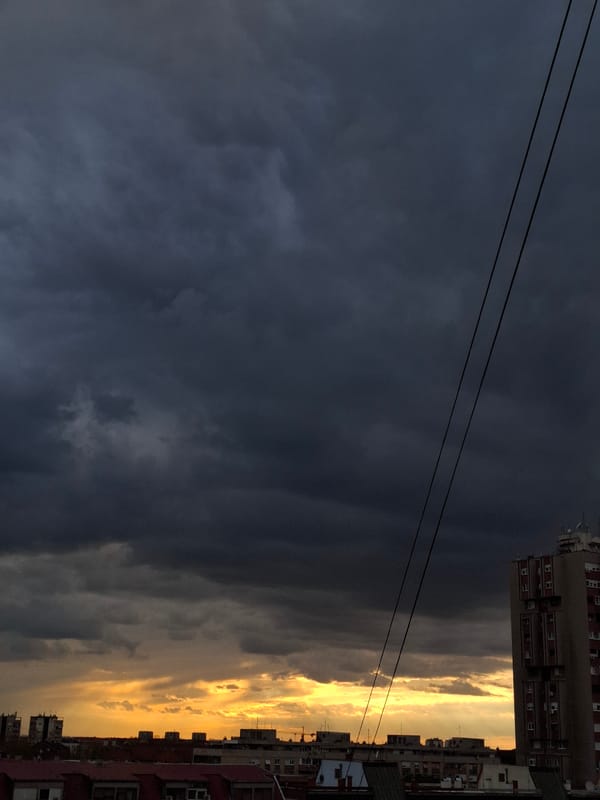 Dramatic storm clouds contrast with golden horizon over city