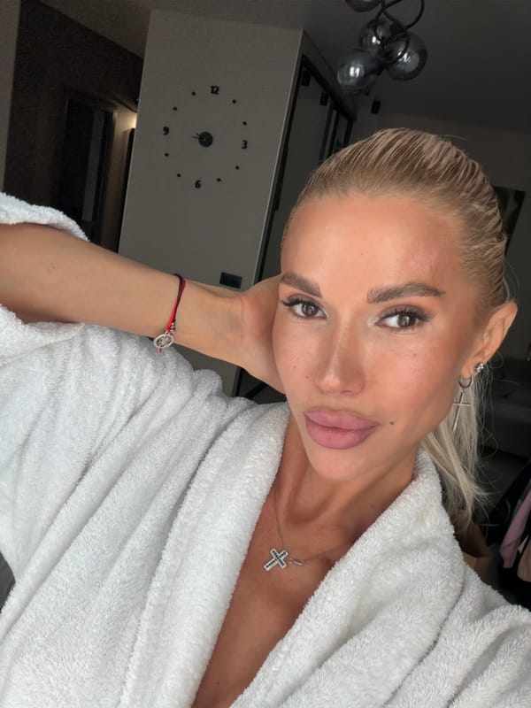 Woman takes selfie in bathrobe with cross jewelry