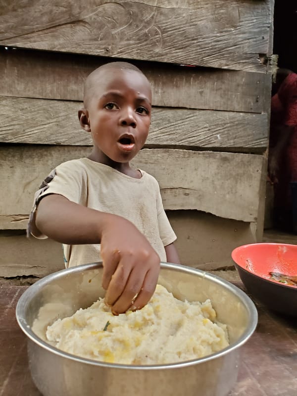 Child reaches for fufu in rustic Nigerian home