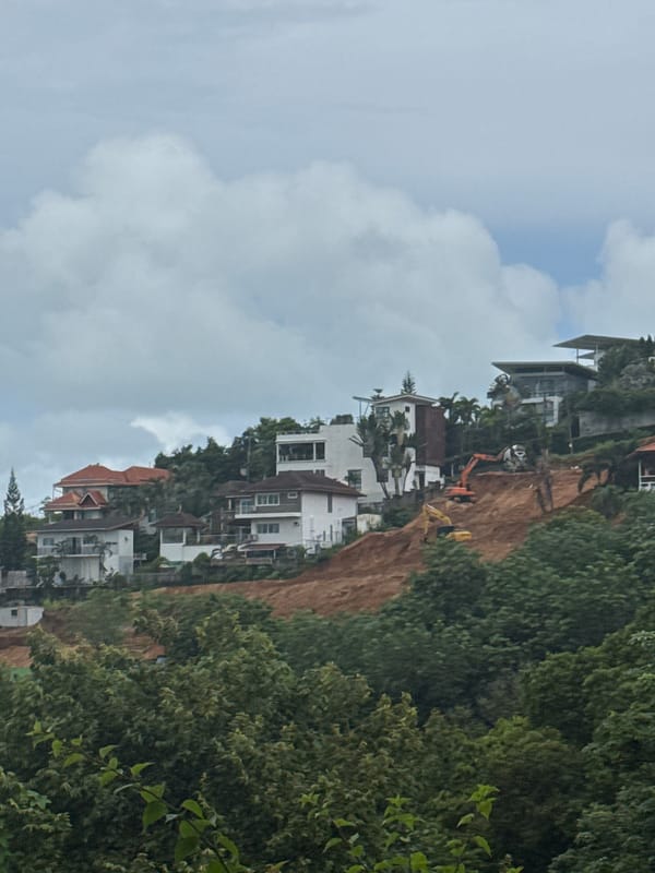 Rawai hillside: resorts, construction, and tropical greenery under grey skies