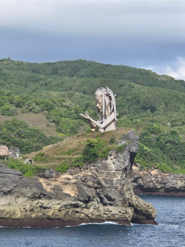 Stone deity sculpture spotted on ocean cliff in Nusa Penida